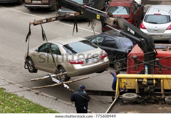 ODESSA,\
UKRAINE - December 7, 2017: Traffic police officers pick up towed\
car on tow truck. Car is loaded onto tug, to platform of auto tow\
truck. Emergency towing of car on forklift\
truck