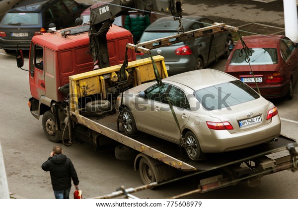 ODESSA,\
UKRAINE - December 7, 2017: Traffic police officers pick up towed\
car on tow truck. Car is loaded onto tug, to platform of auto tow\
truck. Emergency towing of car on forklift\
truck