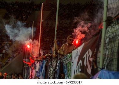 ODESSA, UKRAINE - July 15, 2017: Super Cup. Shakhtar - DYNAMO (Kiev). Fanatical fans in stands during game of eternal rivals. Fans on stands joy, light fire and waving flag. Fiery show at stadium