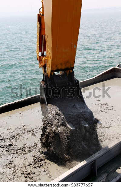 ODESSA, UKRAINE - July 2, 2011: Specialized floating\
excavator cleans marine sediments of river bottom. Deepening of\
shipping fairway seaside building. Dig riverbed sediments in port\
water area