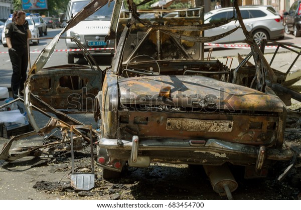 ODESSA, UKRAINE - July 24, 2017: Police,\
explosives technicians, forensics inspect  car burned from an\
explosive as result of terrorist act. Blown up, burned car. police\
work at crime scene.\
Terror
