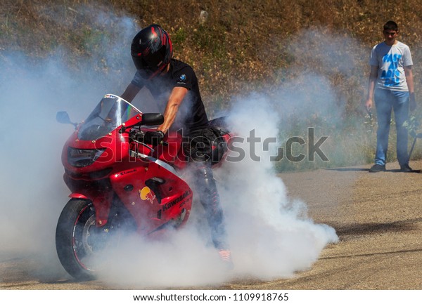 ODESSA, UKRAINE - June 10, 2018: Auto show.\
Extreme tricks, drifting on motorcycles, legendary Mustang car.\
Smoke from warming up wheels in place. Drift on site. Extreme auto\
show of speed racing
