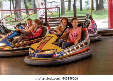 Odessa, Ukraine - June 13, 2016: A group of happy children, boys and girls having fun and joy ride in bumper car on fairground rides at an amusement park. City theme park entertainment
