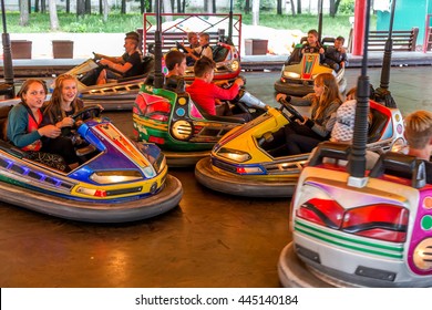 Odessa, Ukraine - June 13, 2016: A group of happy children, boys and girls having fun and joy ride in bumper car on fairground rides at an amusement park. City theme park entertainment