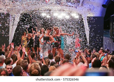 Odessa, Ukraine June 26, 2015: Ibiza Party. Night Party Festival Crowd Of People Silhouettes Hands Up With Confetti. Nightclub Party. Colorful Lights During Dj Party At Concert In Night Club.