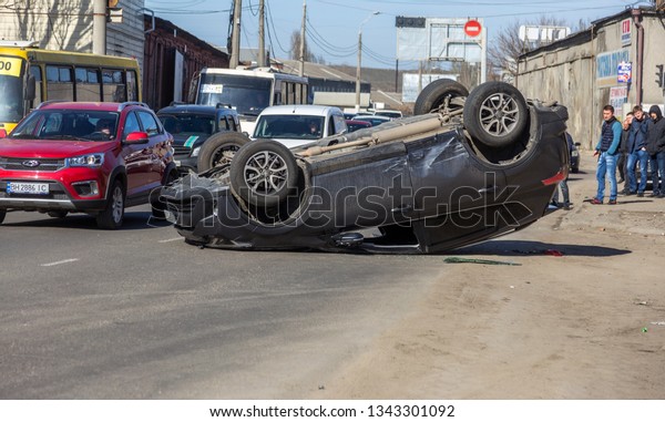 ODESSA, UKRAINE March 19, 2019: after car accident,
broken car rolled over and lay down on roof on road that other cars
drive. Concept of careless driving, breaking rules and speeding on
road