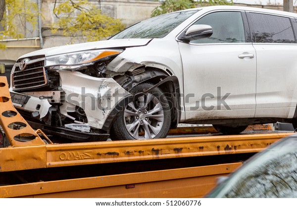 ODESSA, UKRAINE - November 8,2016: Broken car\
after an accident is transported from accident to tow truck. Damage\
after head-on collision jeep loaded on Tow truck for transportation\
to repair shop STO