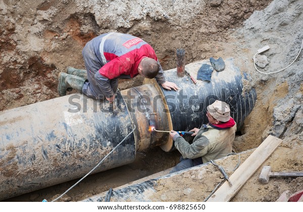 Odessa, Ukraine -\
October 11, 2016: Repair of heating duct. The workers, welders made\
by electric welding and gas welding on large iron pipes at a depth\
of excavated trench.