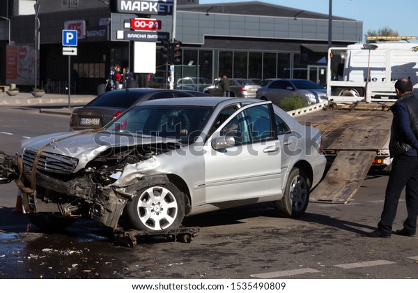 ODESSA, UKRAINE - October 16, 2019: Car accident,\
head-on collision. A tow truck loads a wrecked car after an\
accident. Traffic police officer during an investigation in a\
traffic accident zone