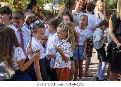 ODESSA, UKRAINE September 1, 2018: September 1, day of the celebration of knowledge. Smiling happy first graders and their happy parents. Teacher in schoolyard holiday Beginning of the training year