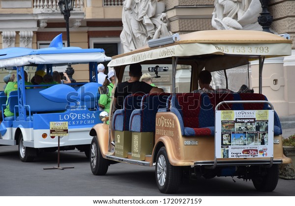 Odessa/Ukraine - July 14, 2019: tourist excursion\
tuk tuks, carts or small buses with some tourists on board near\
Odessa Opera House, back view. Tourism and vacations, city\
excursions on tuk tuk\
buses