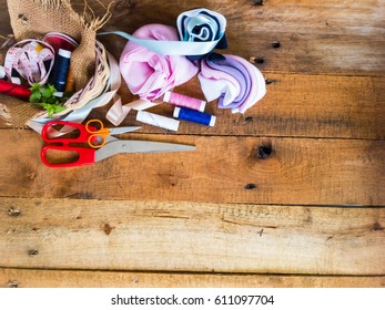 Off cuts of fabric cloth, scissors and colorful threads for needlecraft handmade work on a wooden background wallpaper