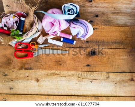 Off cuts of fabric cloth, scissors and colorful threads for needlecraft handmade work on a wooden background wallpaper