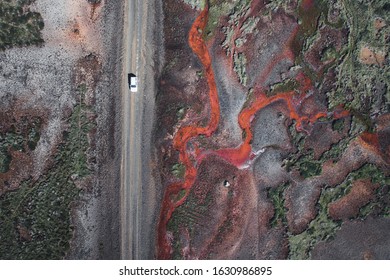 Off road car driving next to the beautiful textured red river. Aerial view of a interesting patterns in Iceland.