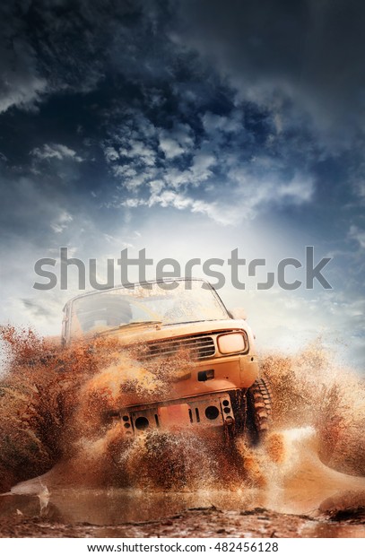Off road vehicle coming out of a mud\
hole hazard,mud and water splash in off-road\
racing.