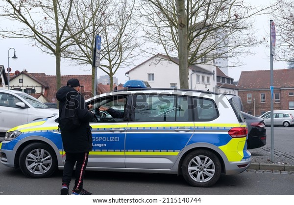 Offenbach, Germany - January 2022: modern car\
on street, man talking to police officer, typical police vehicle in\
city, used to patrol streets, public places, as well as promptly\
respond to incidents
