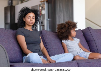 Offended African American Young Mom And Small Daughter Sit Aside On Couch Avoid Talking After Fight, Stubborn Mad Black Mother And Little Kid Ignore Each Other After Quarrel. Family Problem Concept