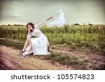 The offended bride with an old suitcase throwing out a wedding veil on the rural road