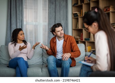 Offended Dissatisfied Angry Emotional Millennial Different Husband And Wife Swear At Meeting With Psychologist In Office Clinic Interior. Psychological Therapy, Family Conflict Resolution And Quarrel