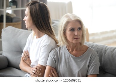 Offended elderly mother and adult daughter sit back to back avoid talking or looking at each other, young woman have disagreement with aged mom, stubborn parent and kid family relationships problems