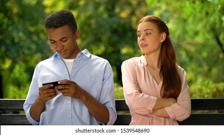 Offended Girlfriend Looking At Boyfriend Chatting On Smartphone, Unfaithful