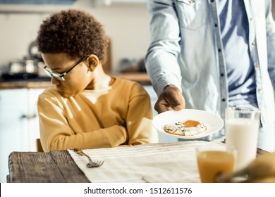 Offended Kid. Impish Boy In Glasses Does Not Want Eggs For Breakfast Today, Even Though His Dad Insists.