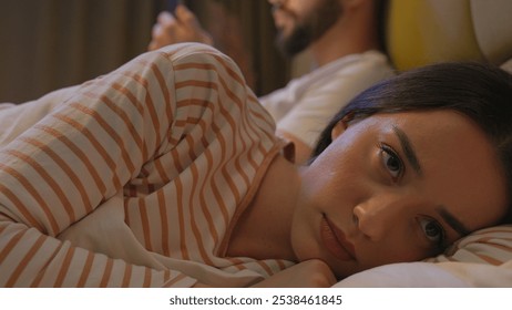 Offended upset girlfriend boyfriend playing mobile phone smartphone stuck relationship dissatisfied woman man couple separation internet displeasure addict ignorance networking bed bedroom together - Powered by Shutterstock