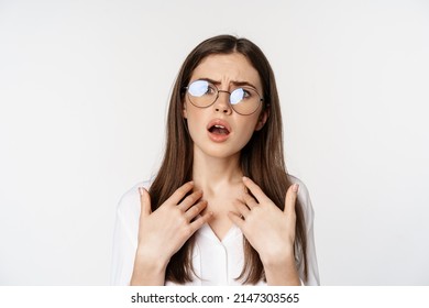 Offended and upset young woman in glasses, beeing jealous or disappointed, feeling hurt, grimacing and sulking, standing confused over white background