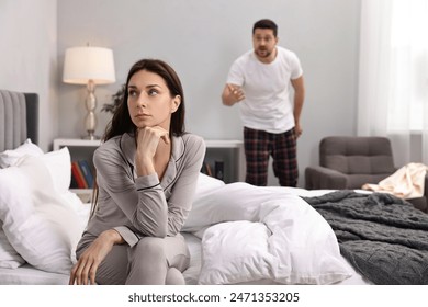 Offended wife ignoring her angry husband in bedroom, selective focus. Relationship problems - Powered by Shutterstock