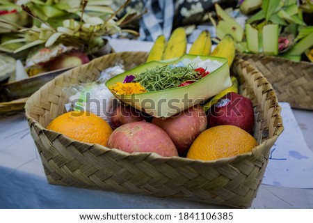 an offering containing fruits in a bamboo basket, and canang sari (something that Balinese Hindus use for praying) on it