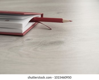 Office accessories: a red notepad and red pencil on a wooden gray desk. Top view. ?lose-up. Copy space.