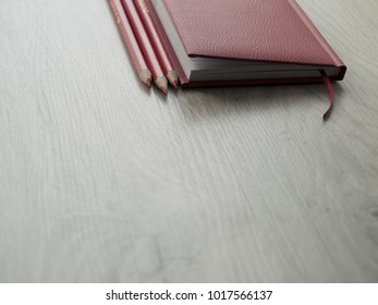 Office accessories: a red notepad and red pencils on a wooden gray desk. Top view, Copy space.