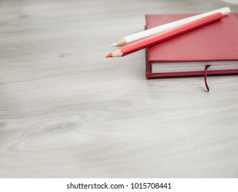 Office accessories: a red notepad, a white pencil and red pencil on a wooden gray desk. Back to school. Top view. Copy space