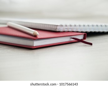 Office accessories: a red notepad, a white notepad and pencils on a wooden gray desk. Back to school. ?lose-up. Top view. Copy space.