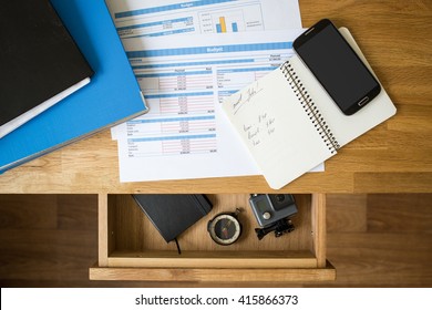 Office accounting stuff vacation concept background. Accounts, smartphone  and binders on the desktop and compass with action camera in the open drawer