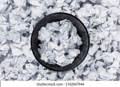 Office Black Garbage Basket Full Stands Among Crumpled Paper, Top View