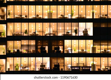 Office Building At Night. Late Night At Work. Glass Curtain Wall Office Building