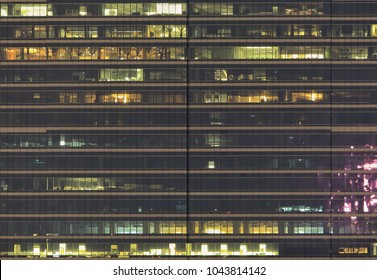 Office Building Side View. People Working During Night In Modern Glass Wall Facade Modern Tower.