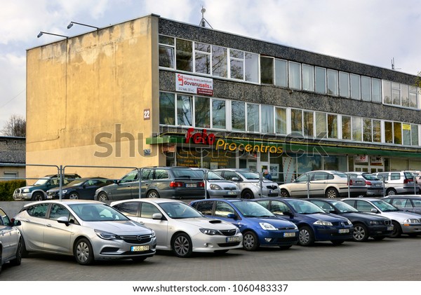 Office building surrounded by cars. Company\'s\
offices. Photo service in Vilnius. Parking area. Modern urban\
cityscape. Life and work in Lithuania. Baltic countries. Lithuania,\
Vilnius - April 27, 2017