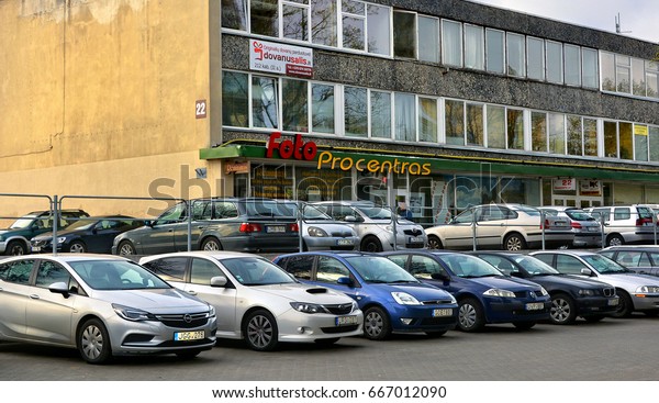Office building surrounded by cars. Company\'s\
offices. Photo service in Vilnius. Parking area. Modern urban\
cityscape. Life and work in Lithuania. Baltic countries. Lithuania,\
Vilnius - April 27, 2017