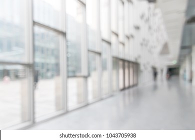 Office Building Or University Lobby Hall Blur Background With Blurry School Hallway Corridor Interior View Toward Empty Corridor Entrance, Glass Curtain Wall, Floor And Exterior Light Illumination