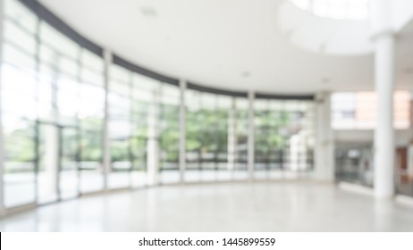 Office Building Or University Lobby Hall Blur Background With Blurry School Hallway Corridor Interior View Toward Empty Corridor Entrance, Glass Curtain Wall, Floor And Exterior Light Illumination