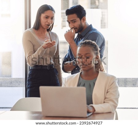 Office bully, woman and working at laptop with coworkers talking in a corporate workplace with gossip. Young black person typing on a computer with internet and joke with staff being mean at desk