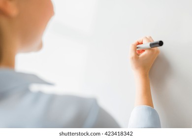 office, business, people and education concept - close up of woman with marker writing or drawing something on white board or wall