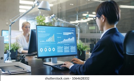 In the Office Businessman works at His Desk, He's Using Personal Computer with Statistical Information Showing on It's Screen. - Shutterstock ID 1064628332