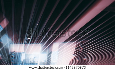 Office ceiling with striped pattern of plenty of parallel long soundproof panels and strong reflections with aberrations