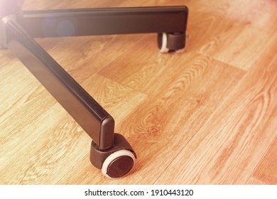 Office chair wheels on a wooden floor in sunlight