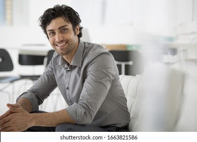 An office in the city. Business. A man seated with his hands clasped in a relaxed pose. Smiling and leaning forwards. - Shutterstock ID 1663821586
