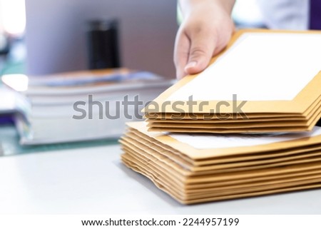 Office clerk or secretary is preparing documents and brown envelopes for those interested in bidding for the construction of a large building in an office.
