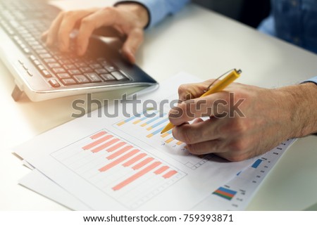 office clerk working with statistical reports and entering data into a computer